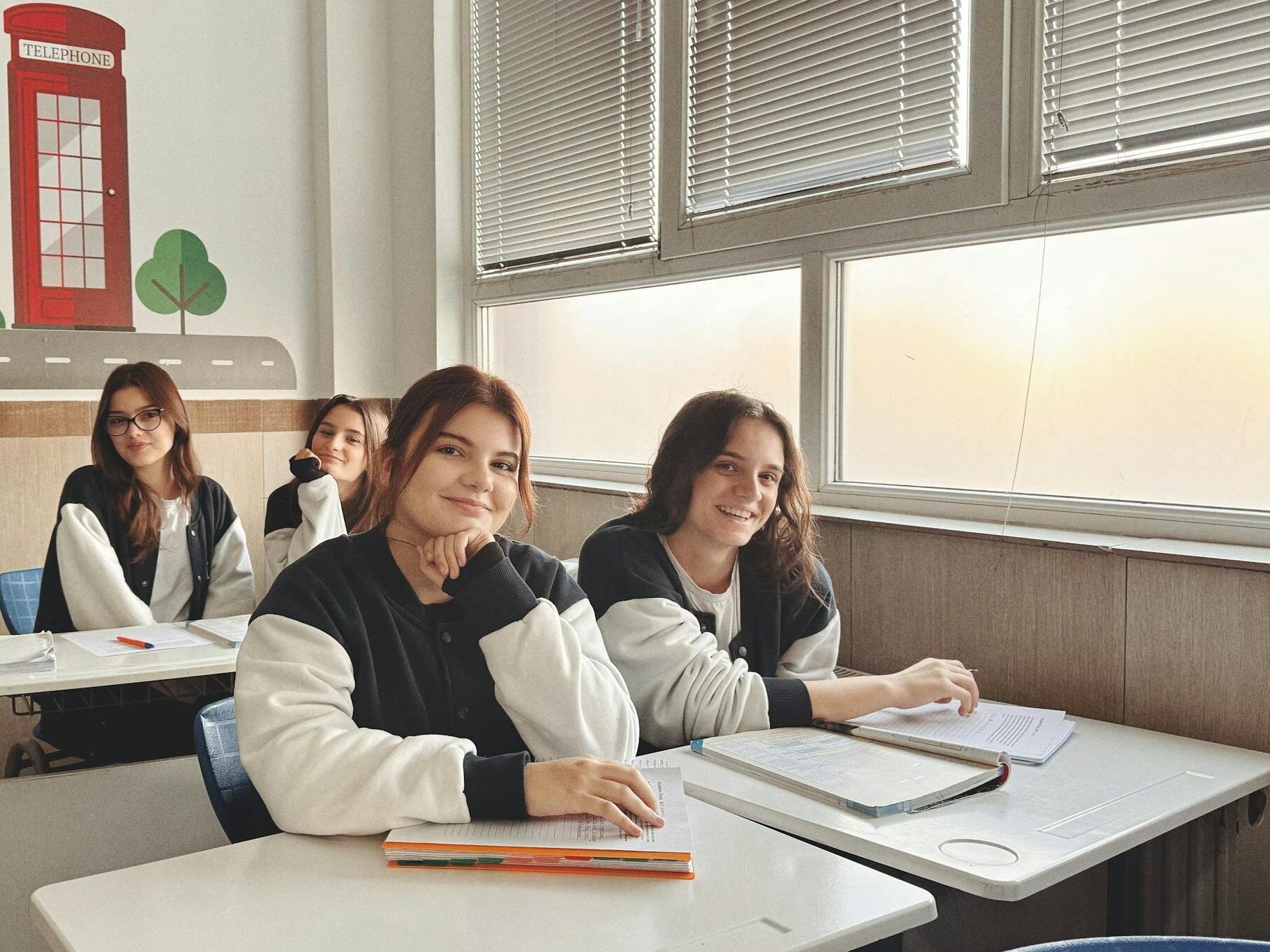 Group of students in a classroom with British decor, studying near a large window.